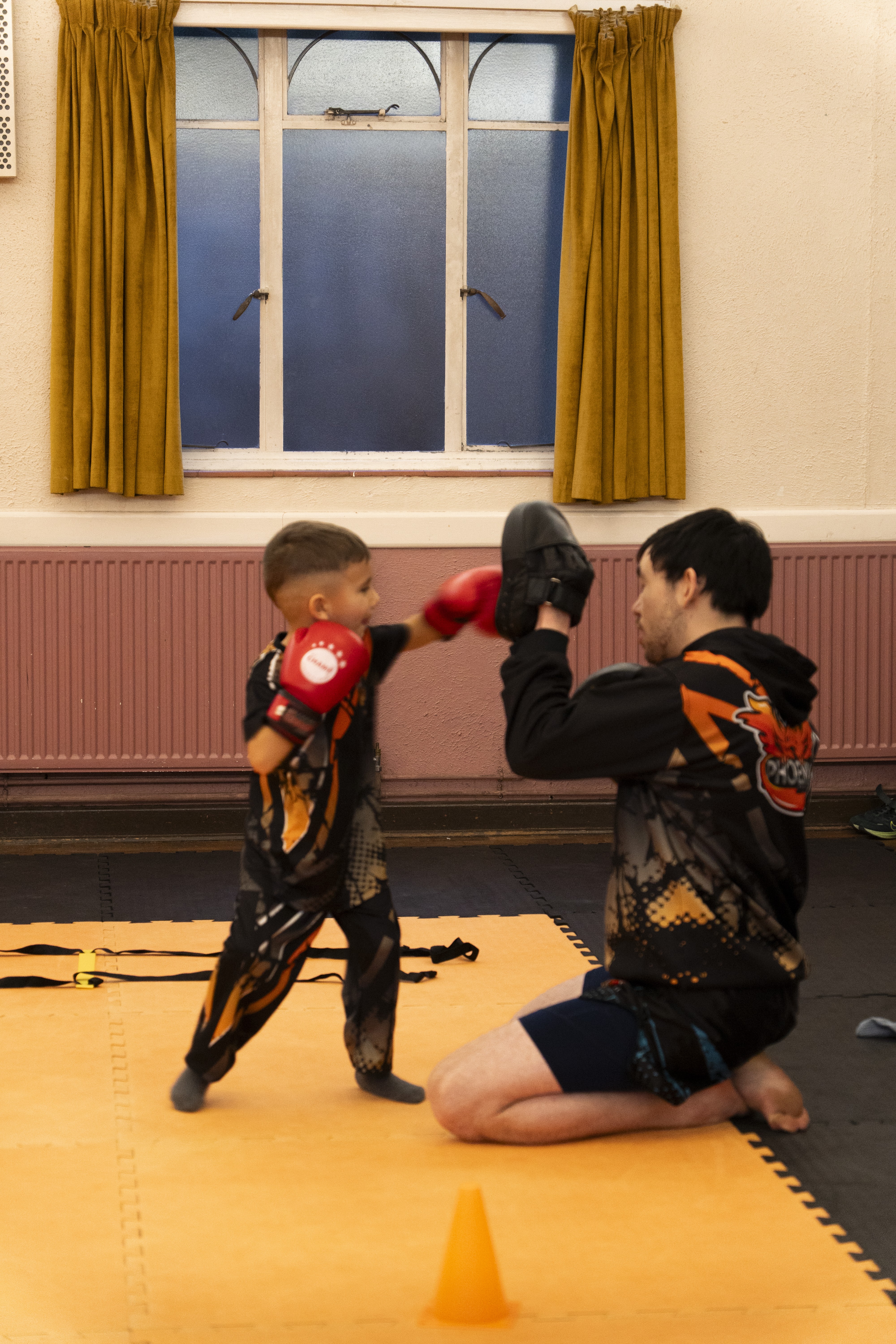 Coach supporting a child during first class pad-work